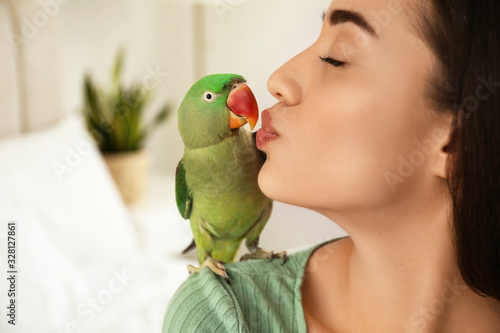 Young woman with Alexandrine parakeet indoors, closeup. Cute pet