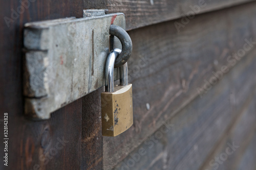 Padlock and steel hasp secure entry to a wooden shed, close up.