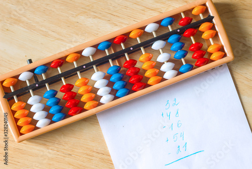 Mental arithmetic and development concept, abacus and mathematical examples on a wooden background