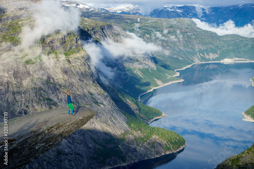 Gymnast standing on his hands on the edge with fjord on background near Trolltunga. Norway