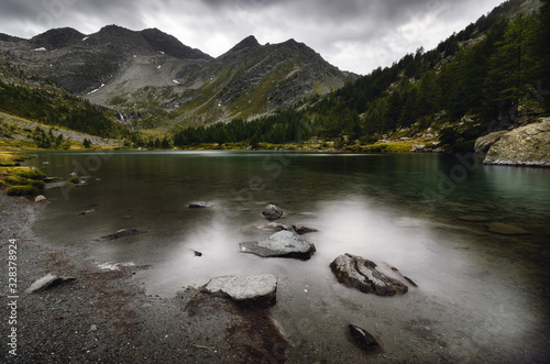 Dramatic sky and water flowing in dark day over the Lac d’Arpy, beautiful alpine mountain lake near Morgex (Aosta Valley, Italy) and the Mont Blanc