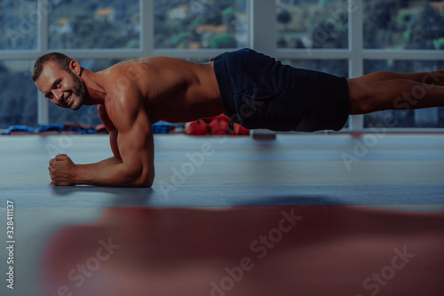 Plank it. Confident muscled young man wearing sport wear and doing plank position while exercising in gym.