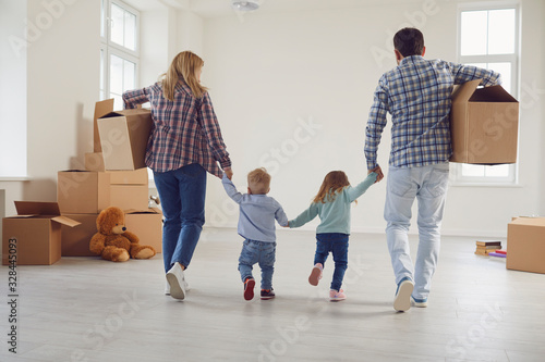 Happy family with children moving with boxes in a new apartment house.