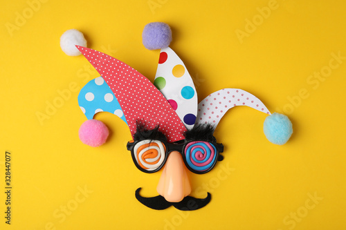 Funny face made of party items on yellow background, flat lay. April Fool's Day