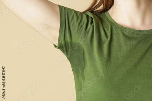 Close up image of woman in green t-shirt with sweat patch under armpit