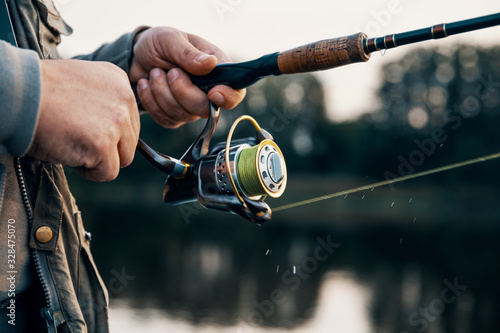 Fishing rod with a spinning reel in the hands of a fisherman.