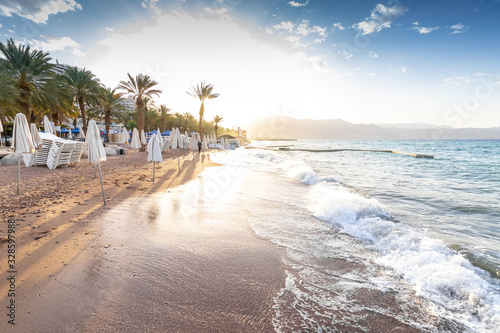 sunrise on the beach. beautiful summer scenery. rocks on the sand. calm waves on the water. clouds on the sky. wide panoramic view