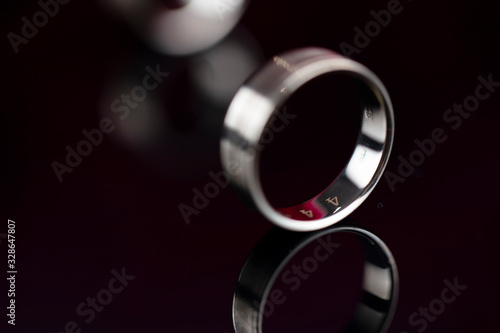 Romantic day concept. Wedding rings lying on shining table on the red roses background. 