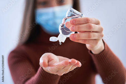 Woman in medical protective mask applying an antibacterial antiseptic gel for hands disinfection and health protection during during flu virus outbreak. Coronavirus quarantine and novel covid ncov