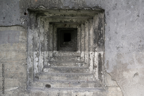 Detail of military bunker and pillbox from world war two - steppen embrasure and hole for gun in the grey wall made of concrete.