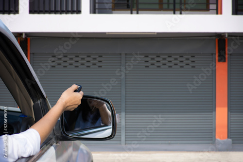 Woman in car, hand holding and using remote control to open the automatic shutter roller steel garage. Security system and wireless concept. Electronic door concept.