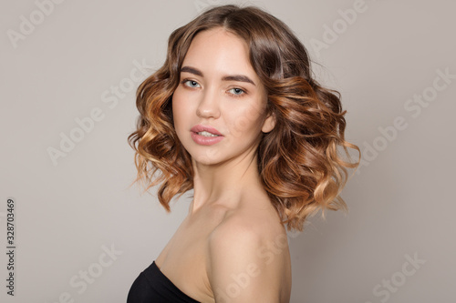 Portrait of a young smiling woman. Voluminous wavy hair. on white background