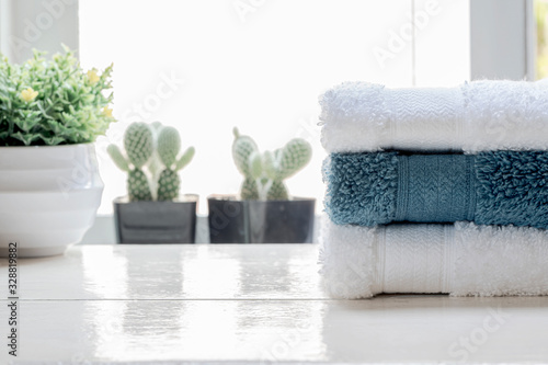 Stack of clean towels and houseplant on white wooden table.