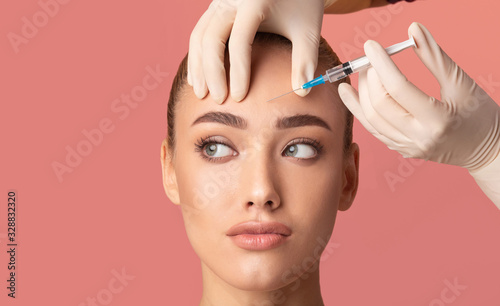 Young Woman Receiving Botox Beauty Injection In Forehead, Studio Shot