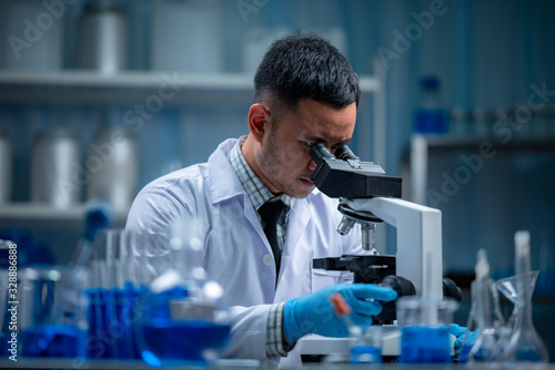 Young scientist looking through a microscope in a laboratory. Young scientist doing some research.