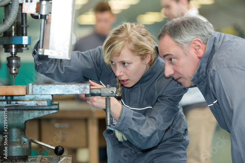 engineer training female apprentice on milling machine
