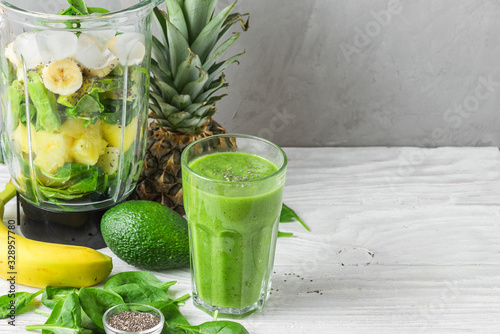 Glass of green smoothie detox with fresh juicy ingredients in blender for making healthy drink