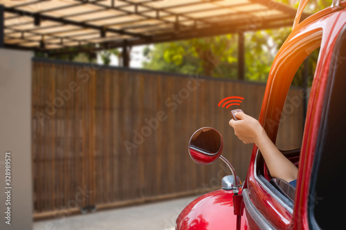 Woman inside red car, hand pressing remote control to open or close the electric sliding auto door.Home remote control, auto garage, security system in concept. 