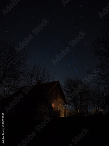 Slightly lit cottage under night sky with stars