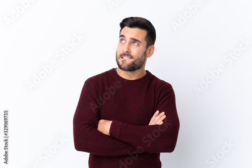 Young handsome man with beard over isolated white background with confuse face expression