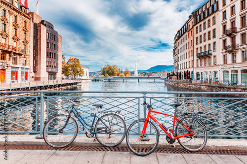 Switzerland, Geneva city. Classical view of Swiss famous city Geneva - capital buildings at lake Geneva banks and bicycles at pedestrian bridge.