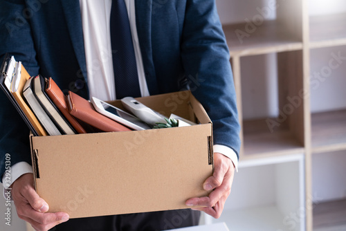 Sad Fired Young Employee businessmen hold boxes including pot plant and documents for personal belongings unemployment, resigned concept.