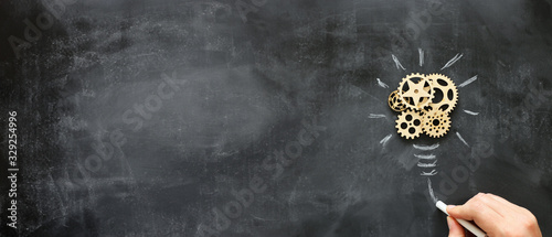 Education concept image. Creative idea and innovation. Wooden gears light bulb metaphor over blackboard