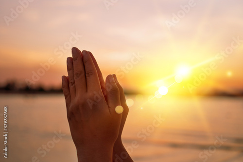 Woman hands place together like praying in front of nature green background.