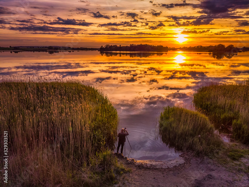 Fotograf nad jeziorem w czasie zachody słońca