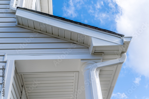 Classic white gutter system that collects water shedding off the roof, with slip connector, end cap, elbow tube, gutter hanger, gutter drop connecting the outlet to the downspout with soffit, fascia