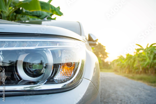 Close up front car's sidelight and projector light with sun warm light in the evening