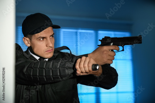 Professional security guard with flashlight and gun in dark room