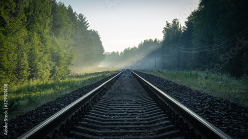 train rails in the sun and electric poles