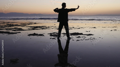 Silhouette man practices qigong exercises, working with qi energy, stand shallow.