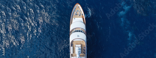 Aerial drone ultra wide top down photo of luxury yacht with wooden deck docked in Aegean island with deep blue sea, Greece