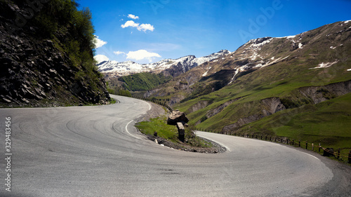 The road is serpentine, a large angle of rotation of the green meadows and the snow