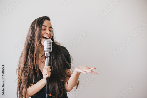 Young beautiful woman sing in vintage microphone.