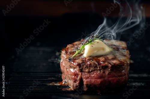 A steaming beef tenderloin steak is grilled in a grill pan with the text copy space. The concept of the recipe , filet Mignon