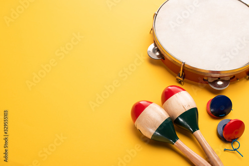 Wooden colorful maracas with tambourine and castanets on yellow background
