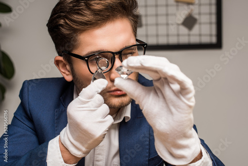 Jewelry appraiser with magnifying glass examining gemstone in workshop