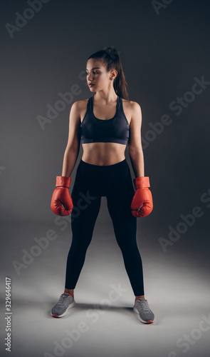 Full-leght Image of a beautiful young amazing sports fitness caucasian woman boxer posing isolated over gray background in red gloves.