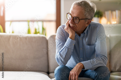 Worried senior man sitting alone in his home