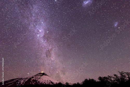 Thousands of stars in the sky with the Milky Way above the Villarrica Volcano in Chile with silhouettes of some trees