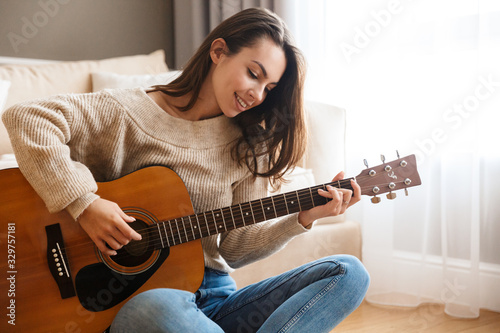 Image of happy beautiful woman playing guitar and composing song