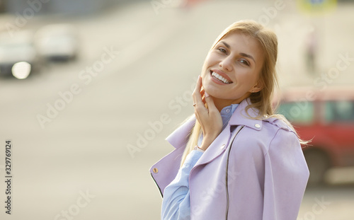 Outdoors lifestyle fashion portrait of happy stunning blonde girl. Beautiful smile. Walking to the city street.