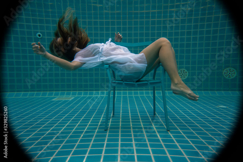 Beautiful woman with long red hair posing underwater on the chair