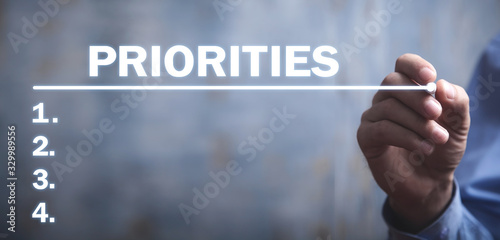 Businessman writing Priorities list in screen.