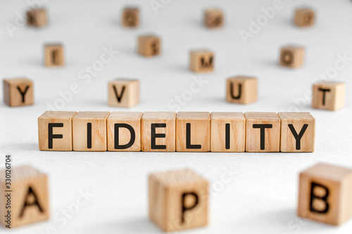 Fidelity - word from wooden blocks with letters, loyalty allegiance fidelity concept, random letters around white background