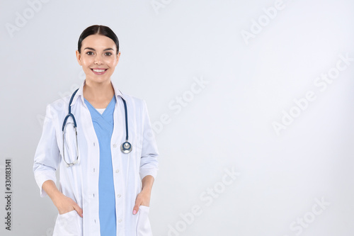 Portrait of young doctor with stethoscope on white background