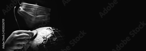 Kid hold globe put stethoscope on sphere, face covered in mask on black horizontal background. Ecological problems disasters. COVID-19 pandemic infection disease concept image, copy space for text